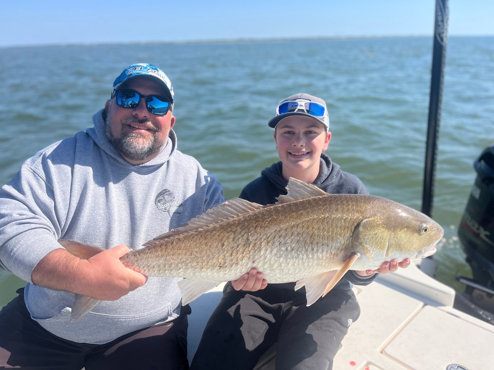 Father and son holding a large redfish on a family-friendly fishing charter in Charleston, SC