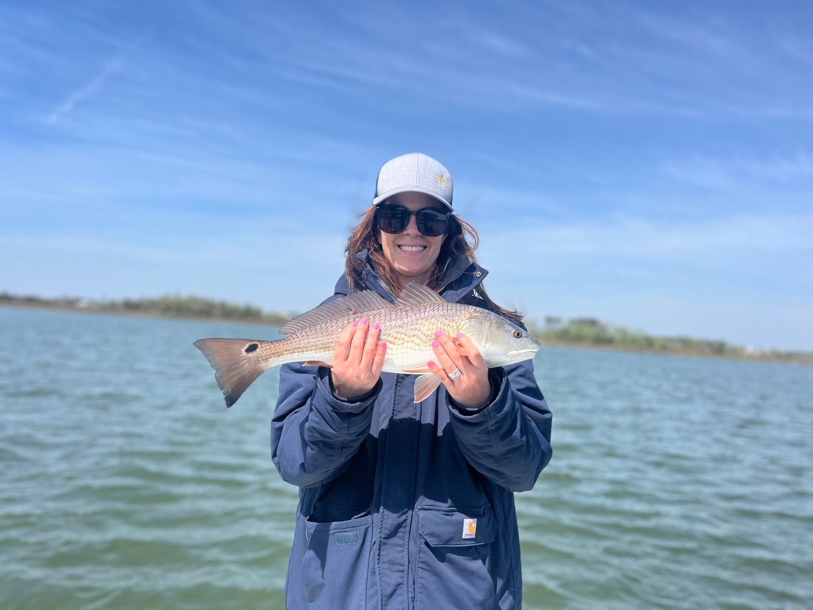 Woman smiling with a freshly caught redfish on the Charleston waterways