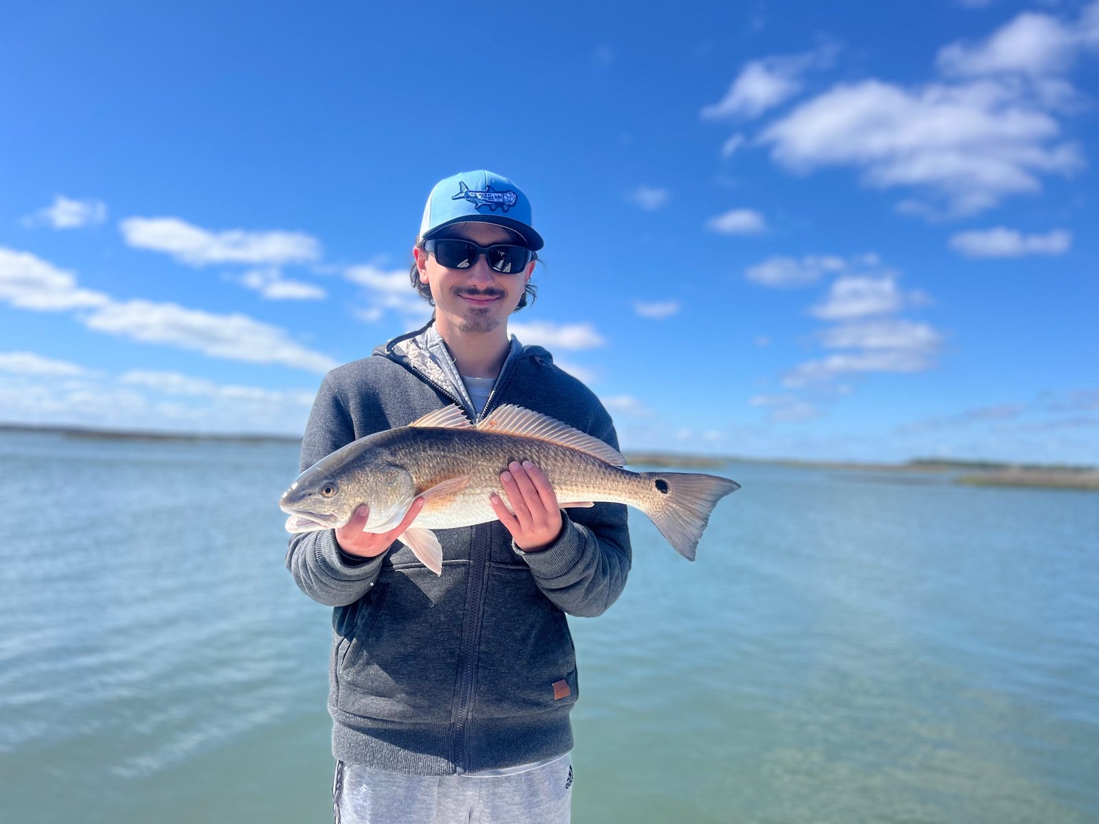 Young man with a redfish caught on an inshore fishing trip with Marsh View Charters